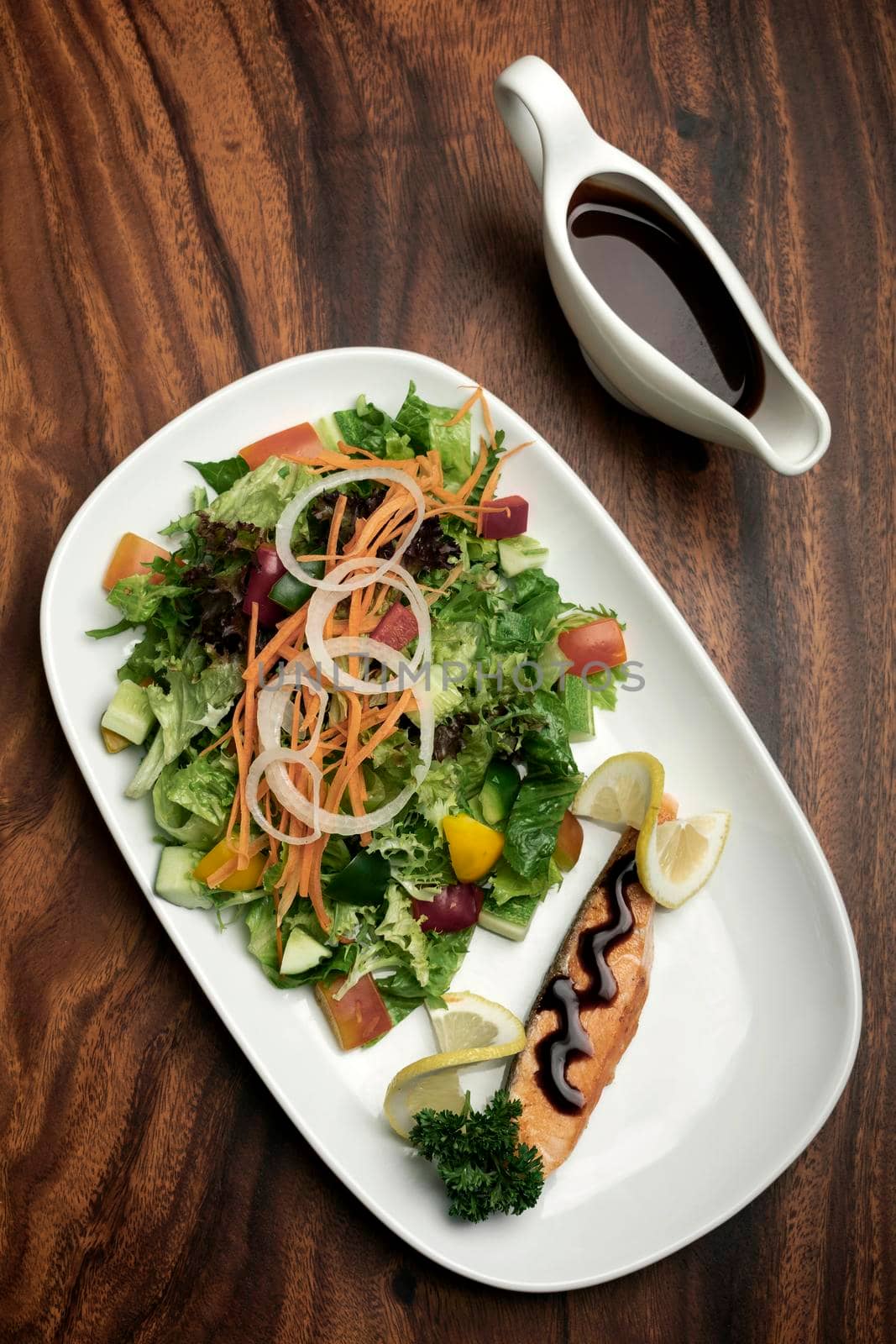 organic mixed vegetable salad with salmon fillet and balsamic vinaigrette on wood restaurant table