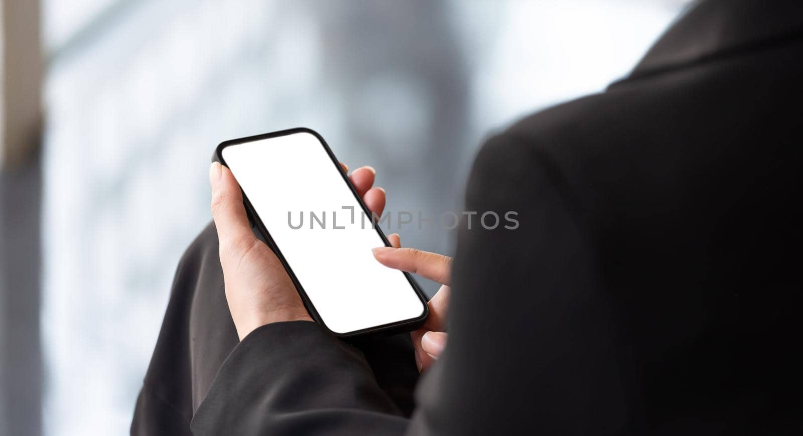 Businesswoman holding smart phone with white blank screen. For Graphic display montage.
