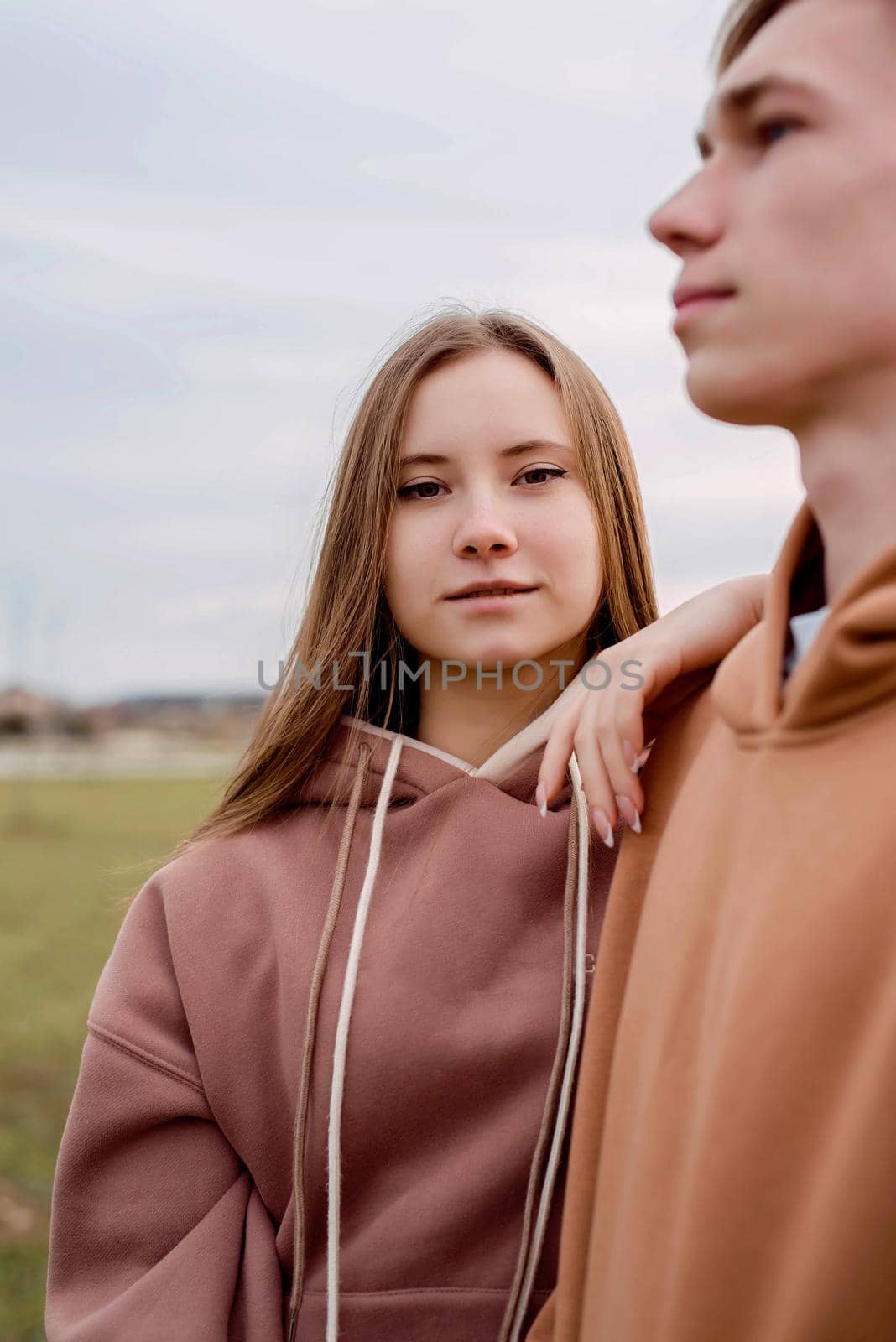 Young couple standing outdoors in cloudy day by Desperada