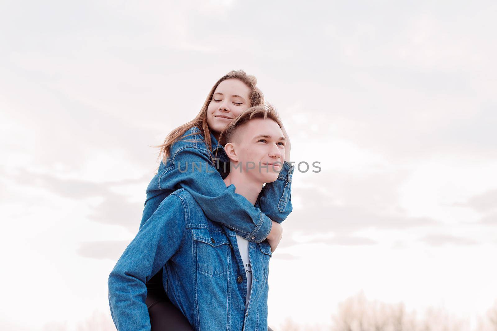 Happy young loving couple embracing each other outdoors in the park having fun