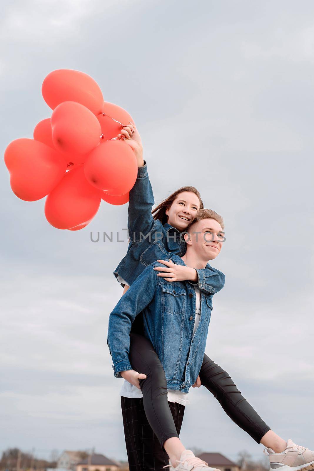 young loving couple with red balloons embracing outdoors having fun by Desperada