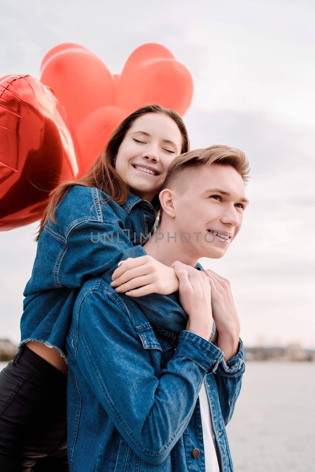 young loving couple with red balloons embracing outdoors by Desperada