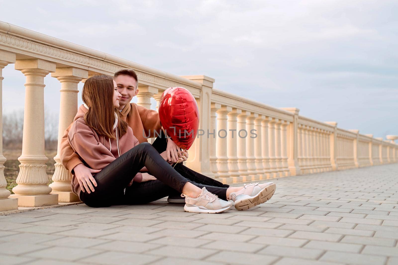 Young loving couple embracing each other outdoors in the park holding balloons by Desperada