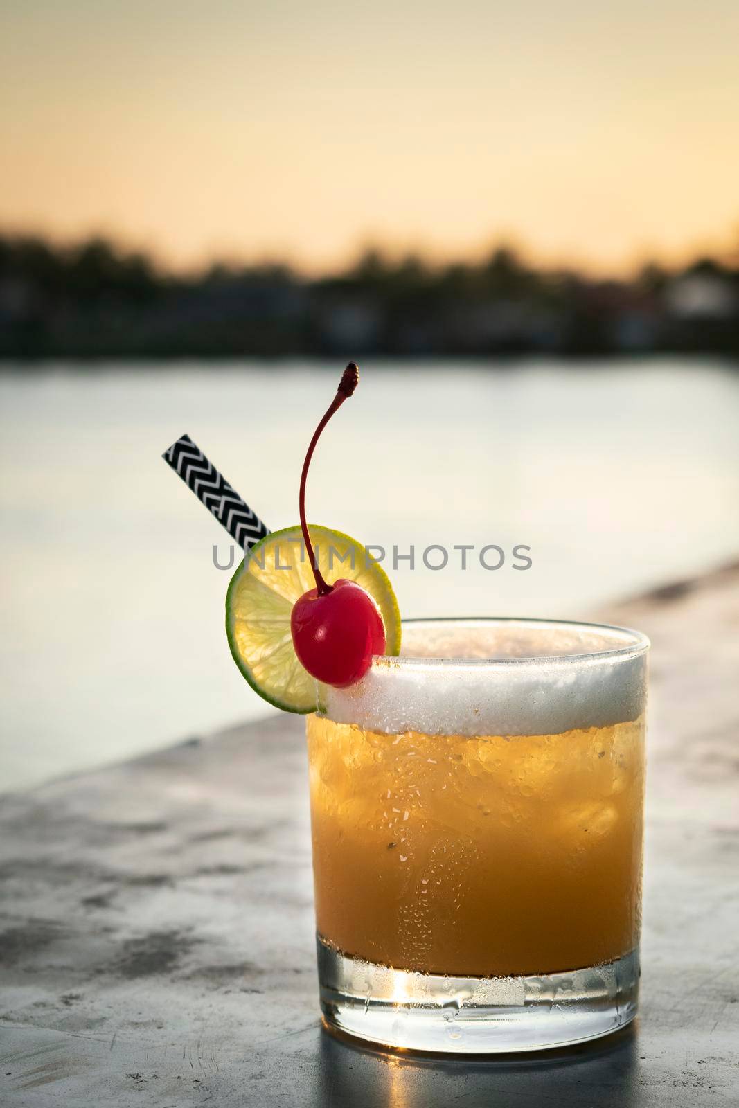 peach screwdriver mixed vodka cocktail drink outdoors at sunset  by jackmalipan