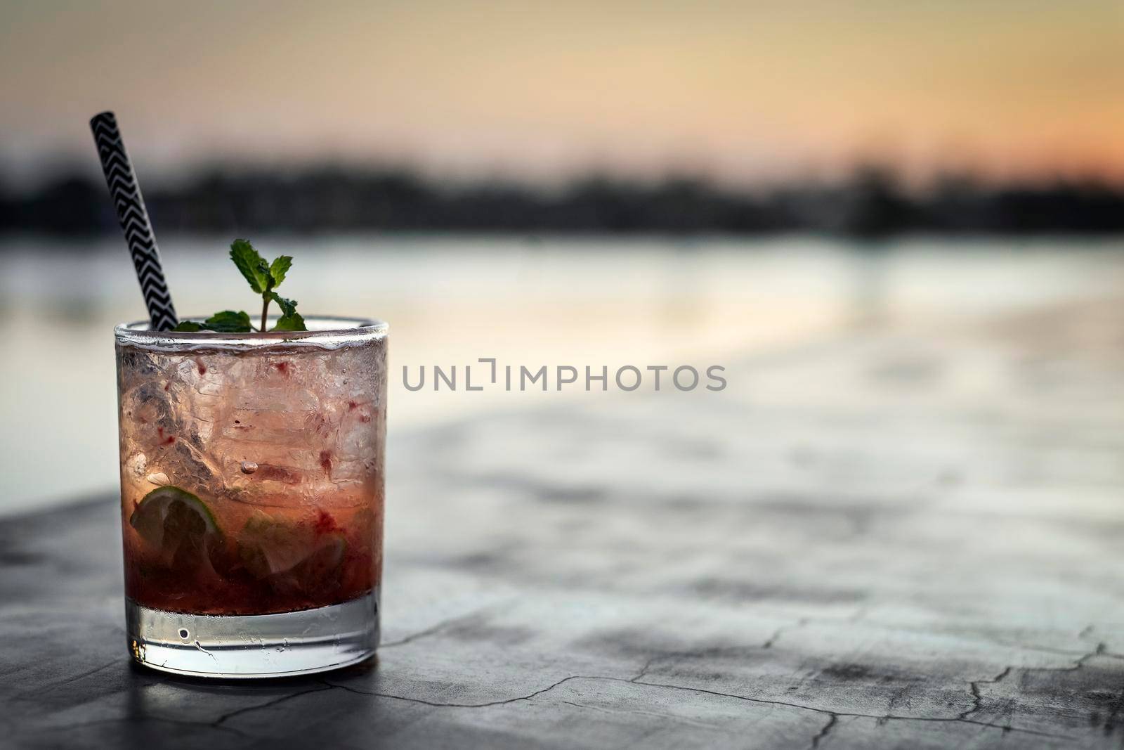 strawberry caipirinha mixed cocktail drink in riverside vientiane laos outdoor bar at sunset