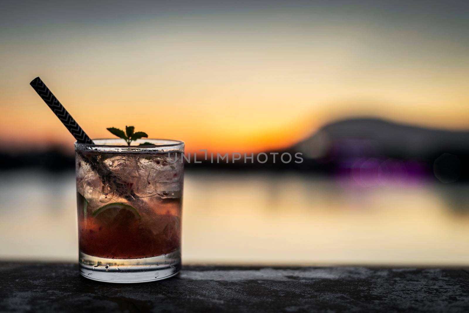 strawberry caipirinha mixed cocktail drink in outdoor bar at sunset by jackmalipan