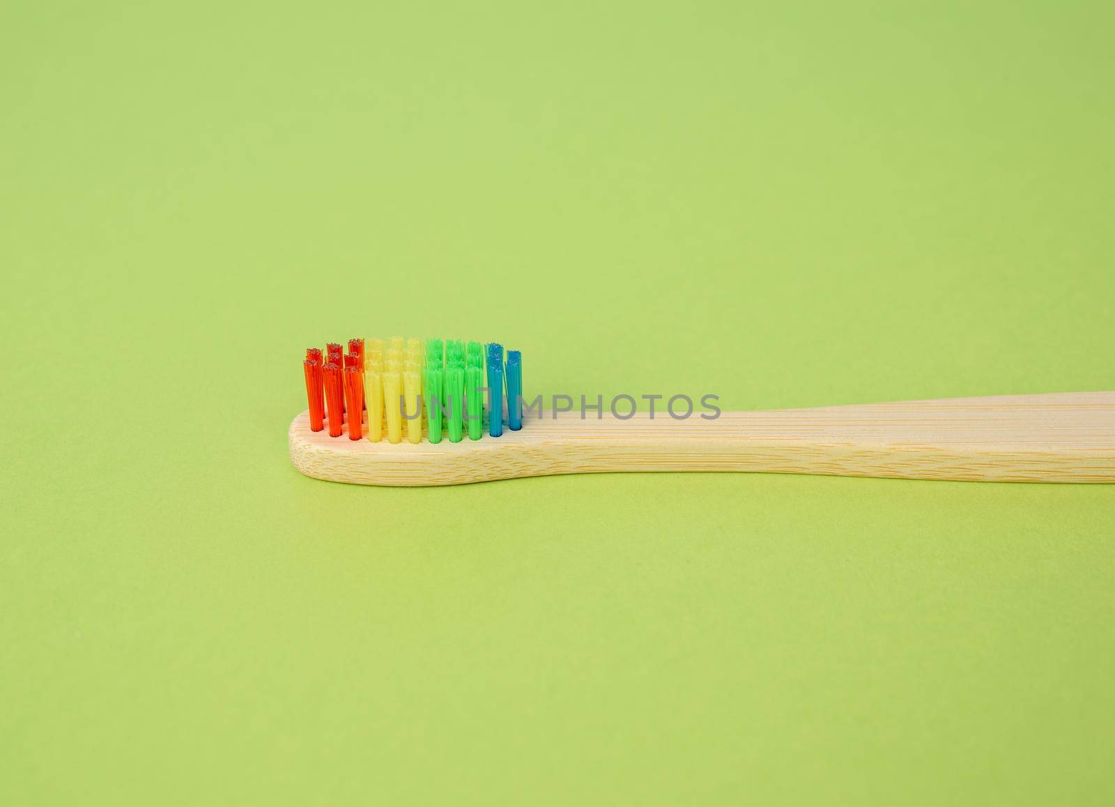 bamboo brush for cleaning teeth on a green background, plastic rejection concept, zero waste, close up