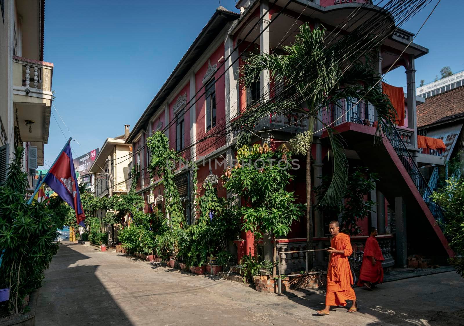 young buddhist monk walking in sunny phnom penh cambodia street inside the Wat Ounalom monastery complex