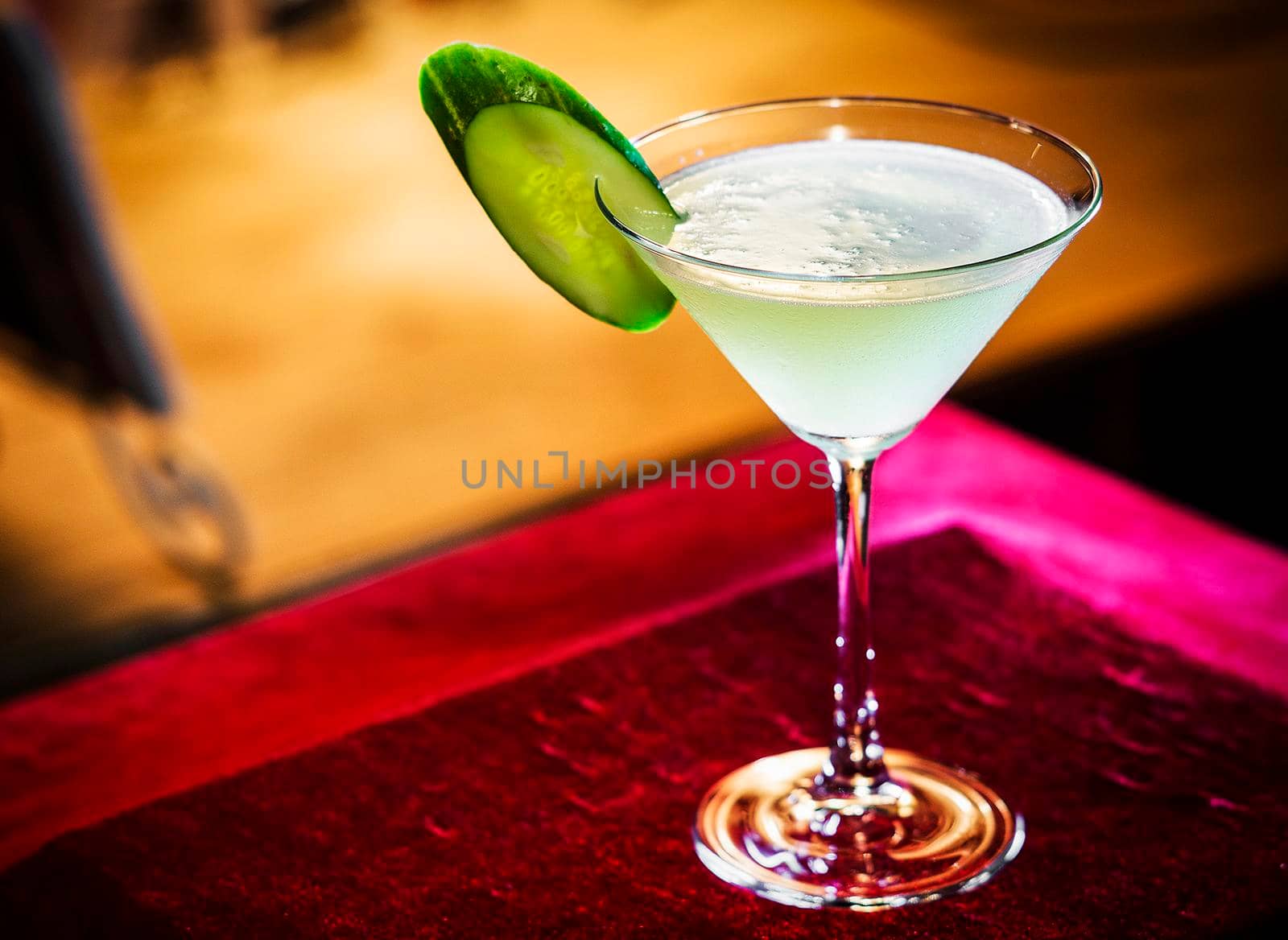 cucumber and lime martini mixed cocktail drink glass inside cozy bar