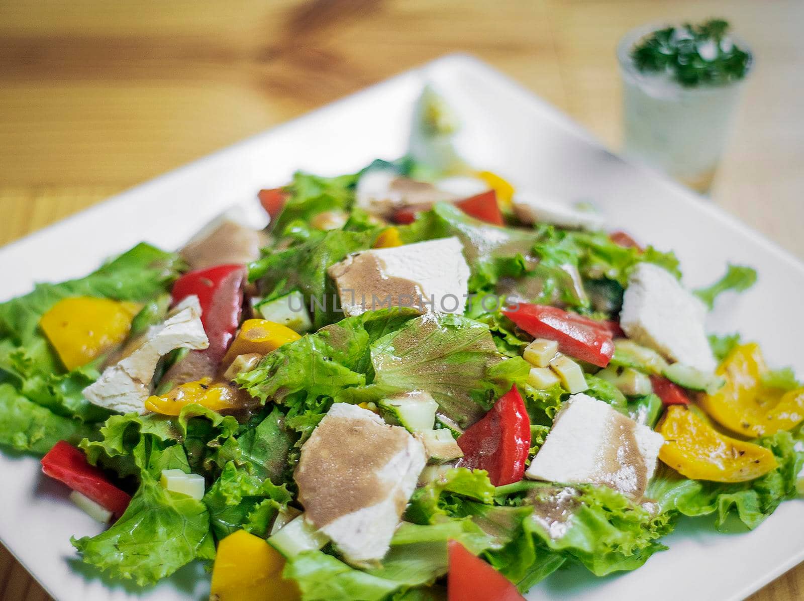 grilled chicken breast mixed fresh vegetable salad on wooden table