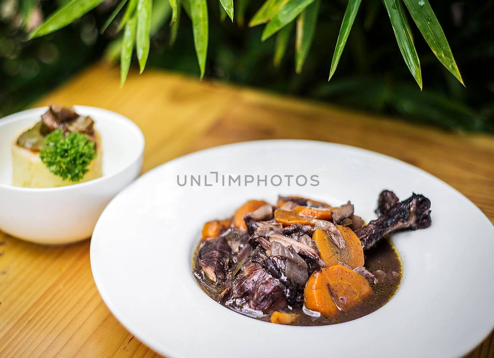 lamb and carrot red wine casserole stew meal on wooden table outdoors