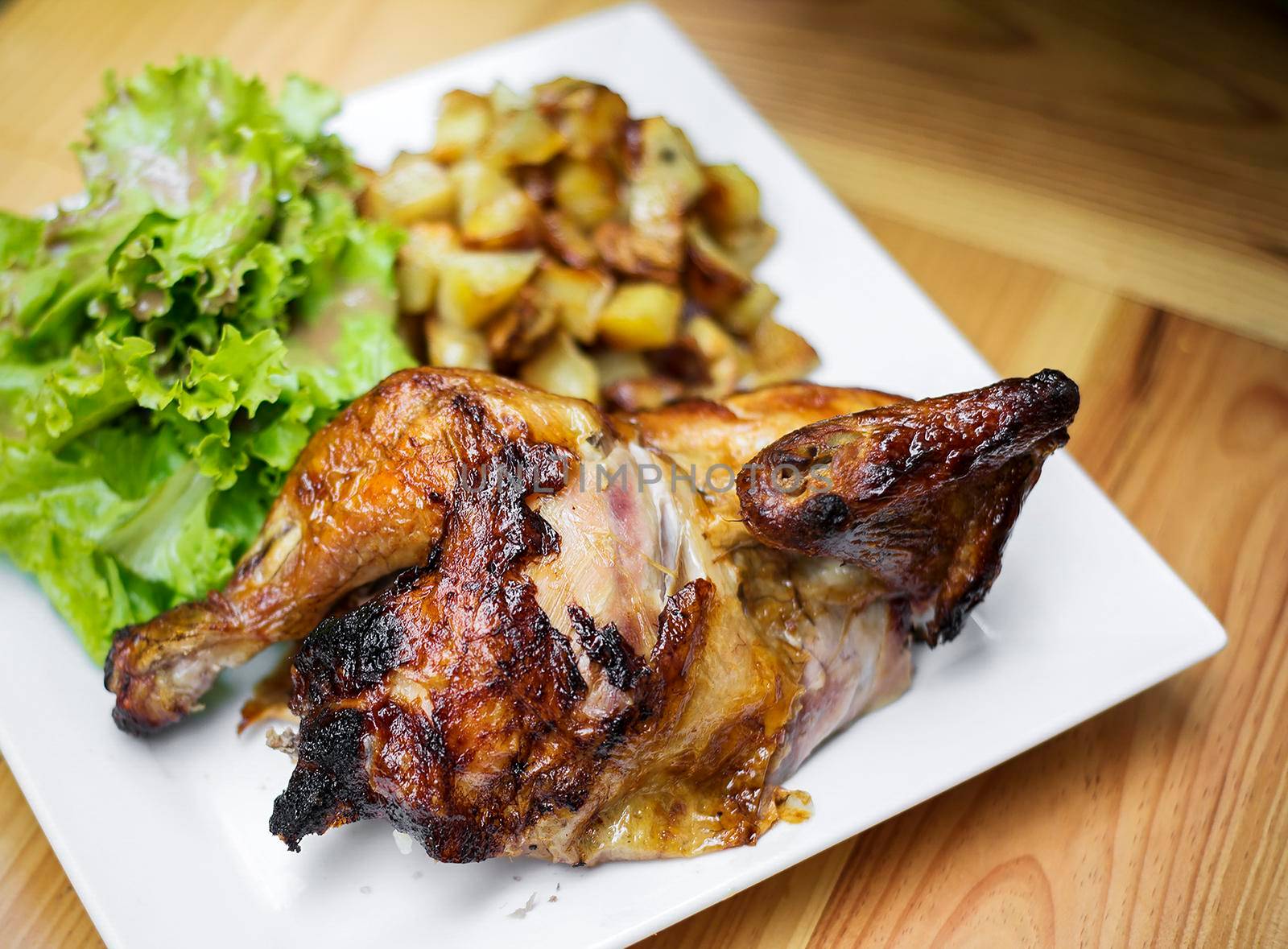 organic roast rotisserie chicken with potatoes and salad meal on wooden table outdoors