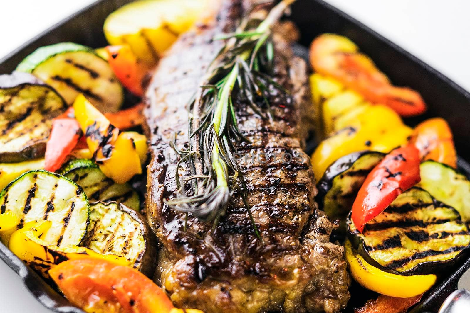 greek organic lamb steak with grilled vegetables and herbs in sizzling skillet