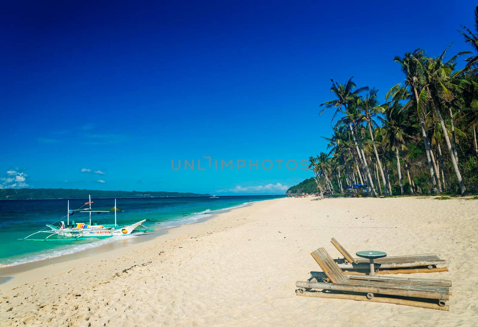 lounge chairs and traditional boat on tropical puka beach in boracay philippines