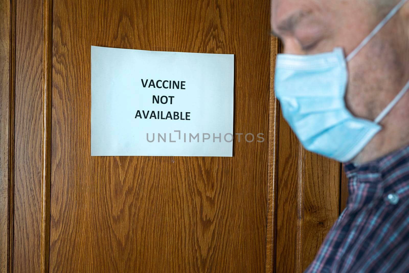 A man in front of a closed door with a sign that reads Closed because the vaccine is not available