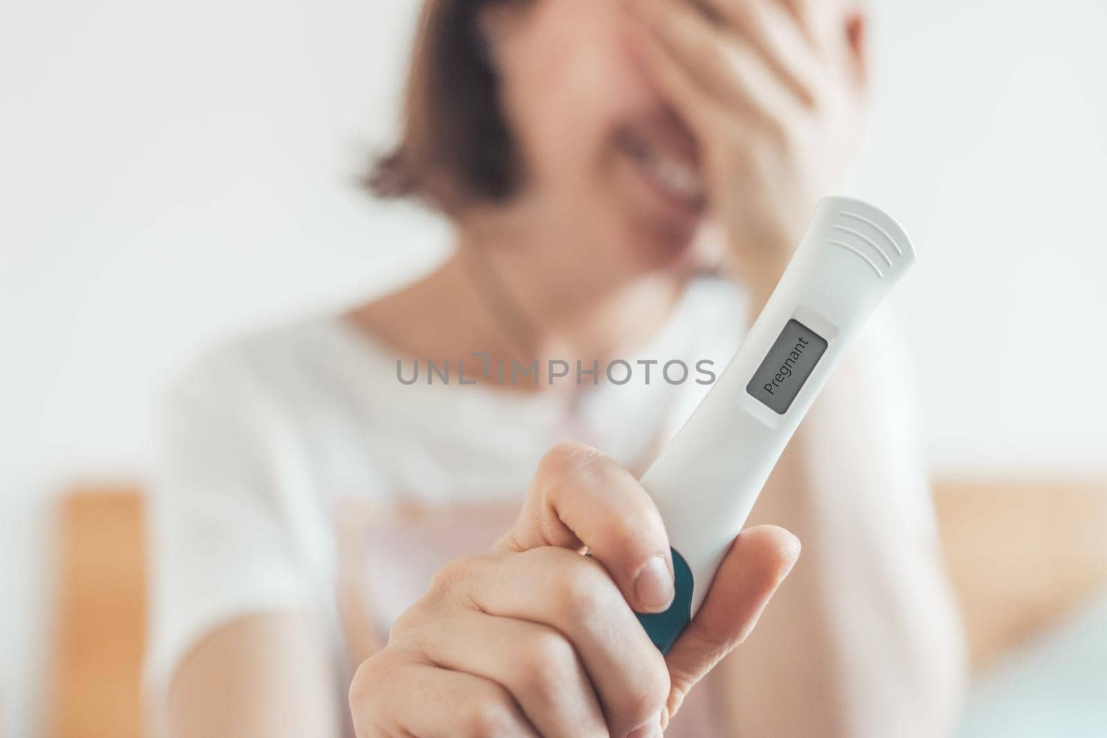 Happy mother holding pregnancy test in her hands, result is pregnant, “Pregnant”