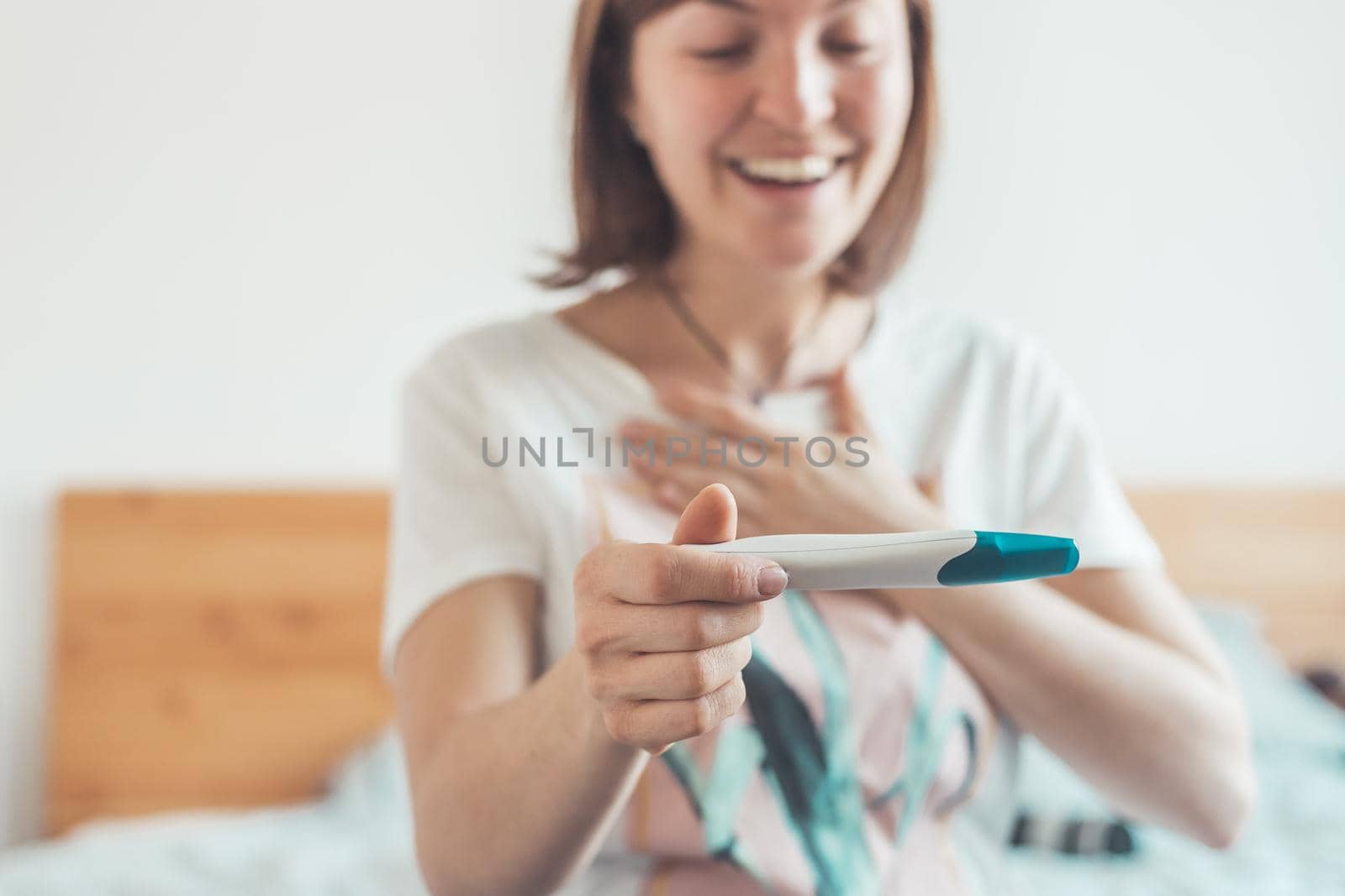 Happy mother holding pregnancy test in her hands, result is pregnant, “Schwanger”