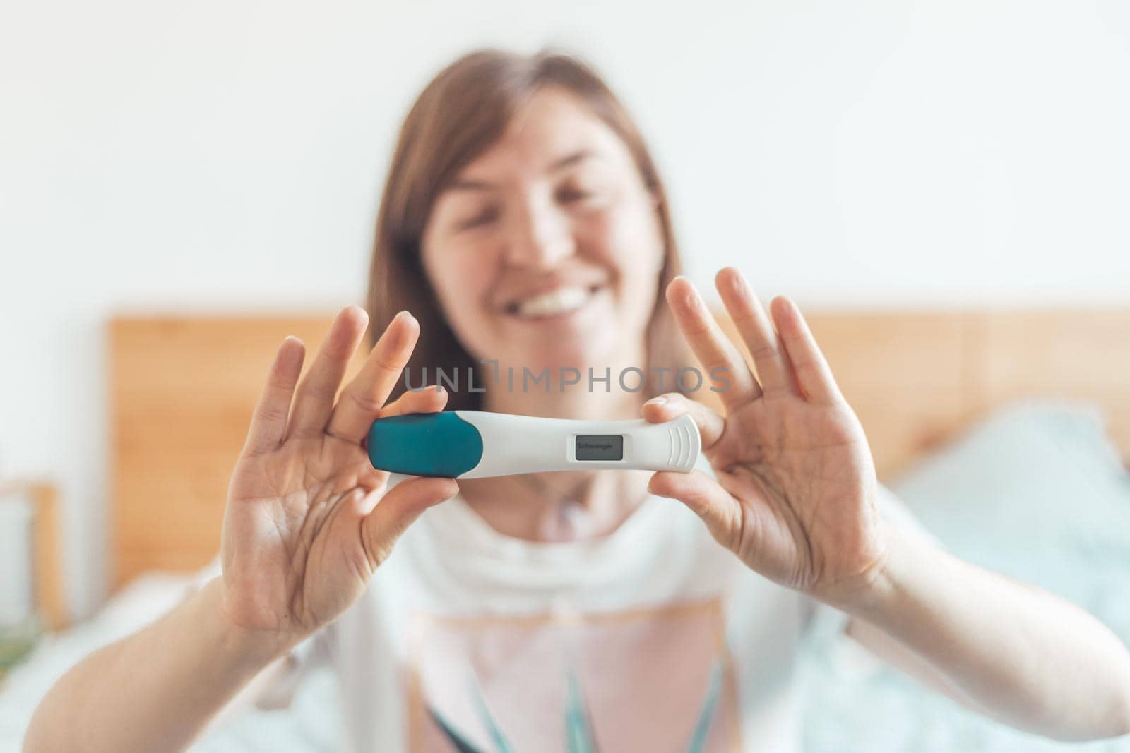 Happy woman sitting on the bed, checking pregnancy test. Result positive, “Schwanger” by Daxenbichler