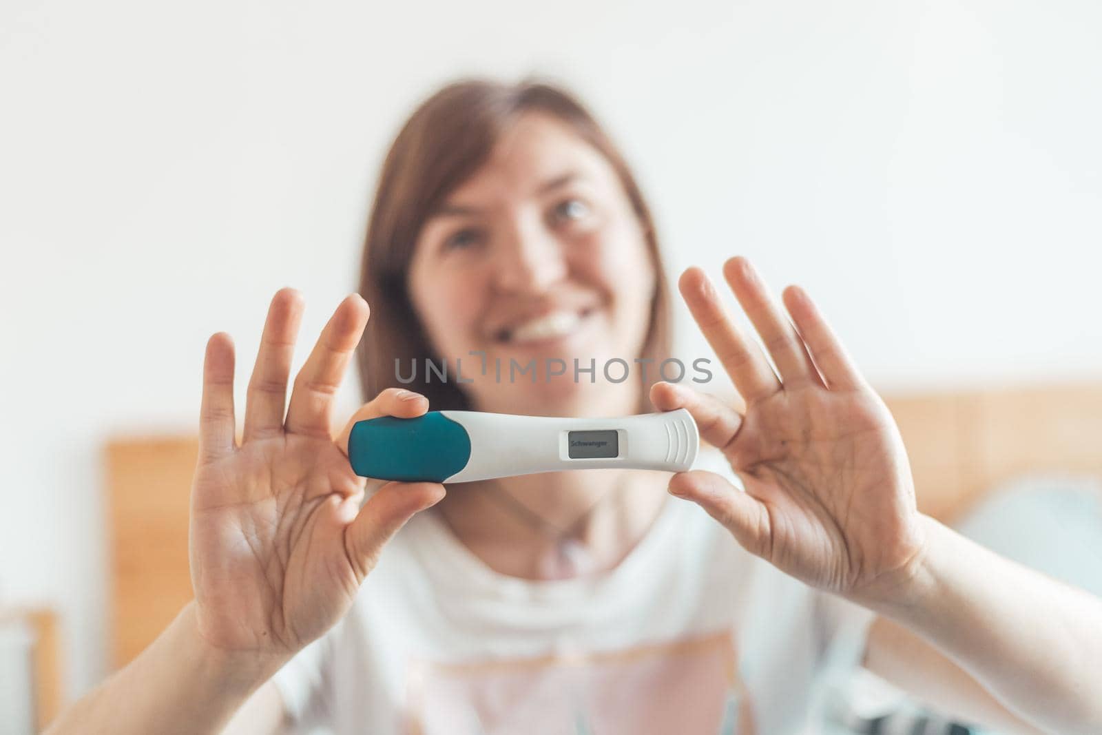 Happy woman sitting on the bed, checking pregnancy test. Result positive, “Schwanger” by Daxenbichler