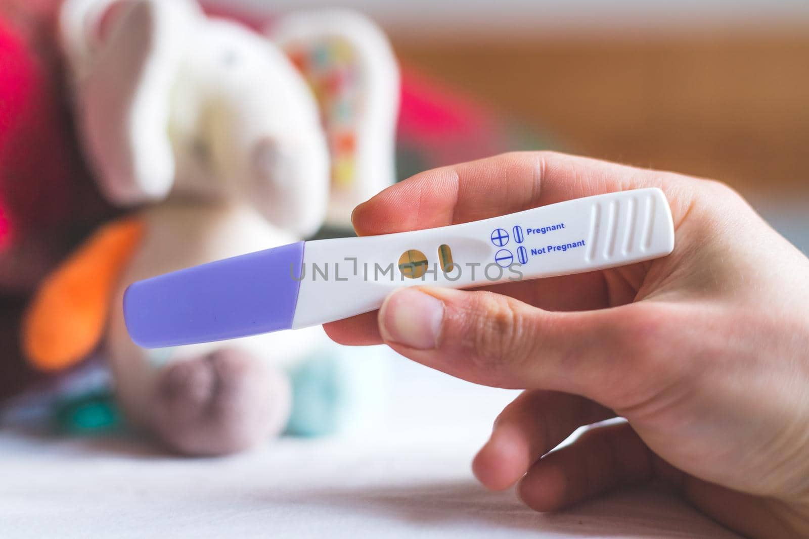 Woman hand holding pregnancy test, result is pregnant