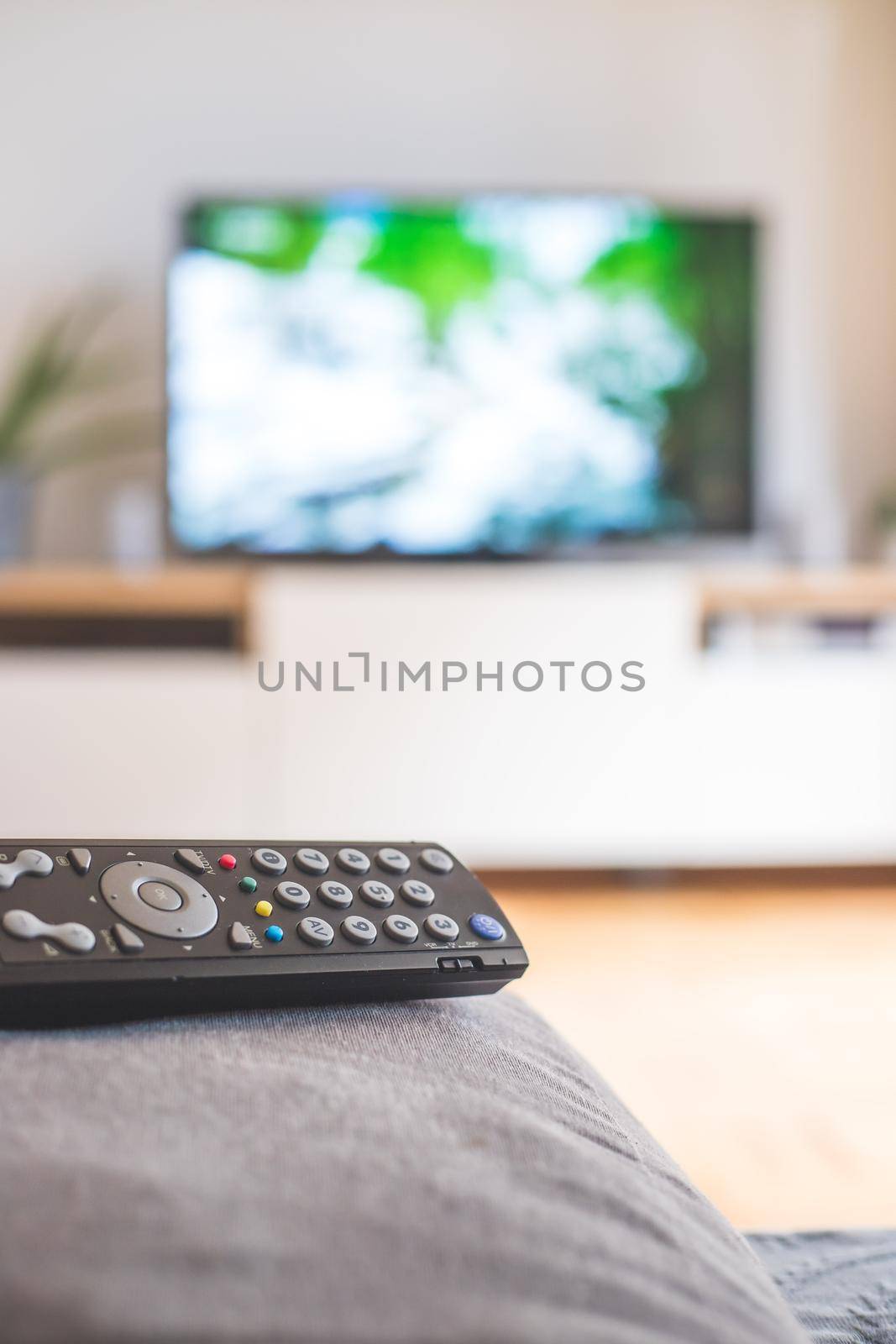Remote control on the sofa, streaming on a smart TV. by Daxenbichler