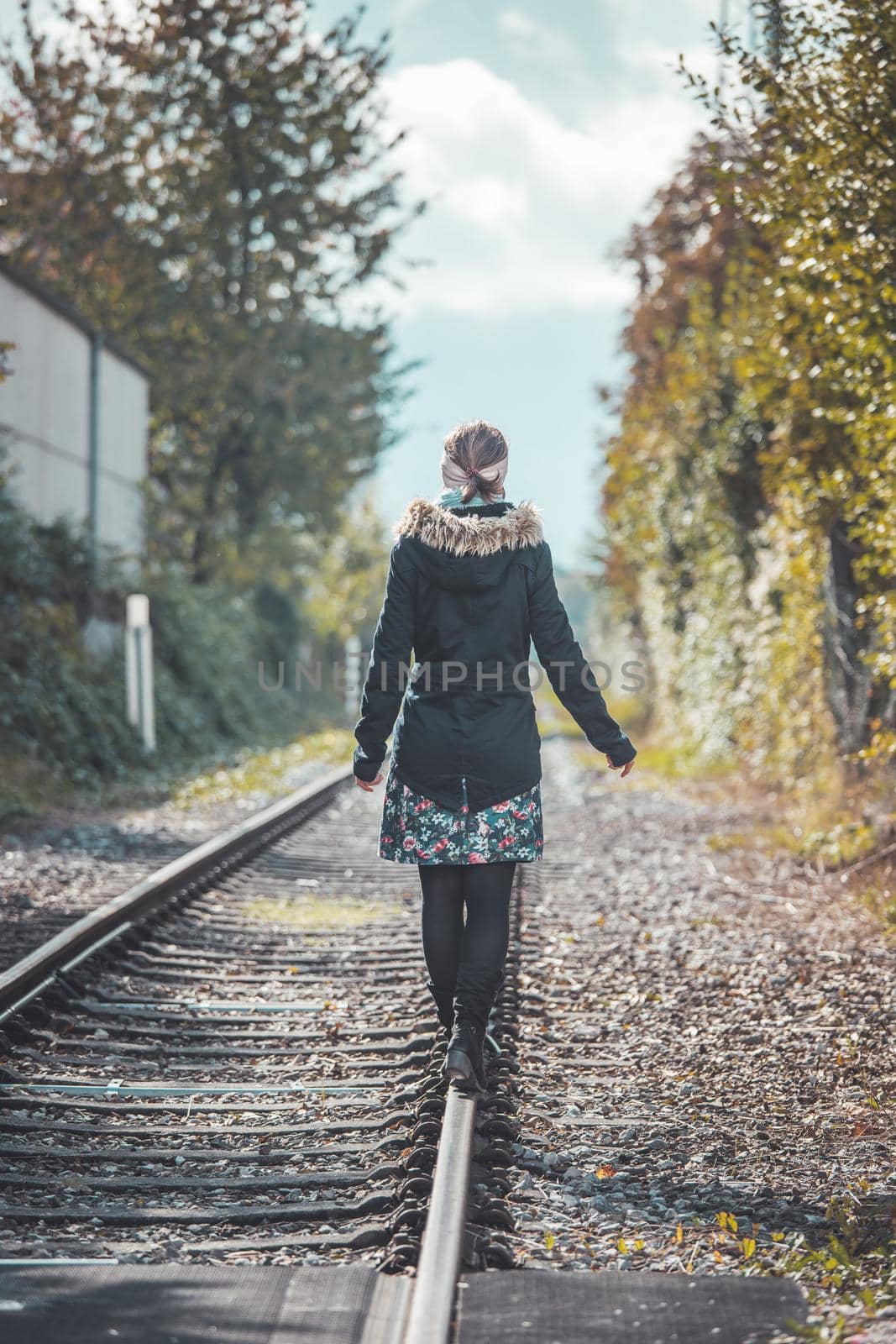 Young pretty girl is balancing on railroad, concept for travelling by Daxenbichler