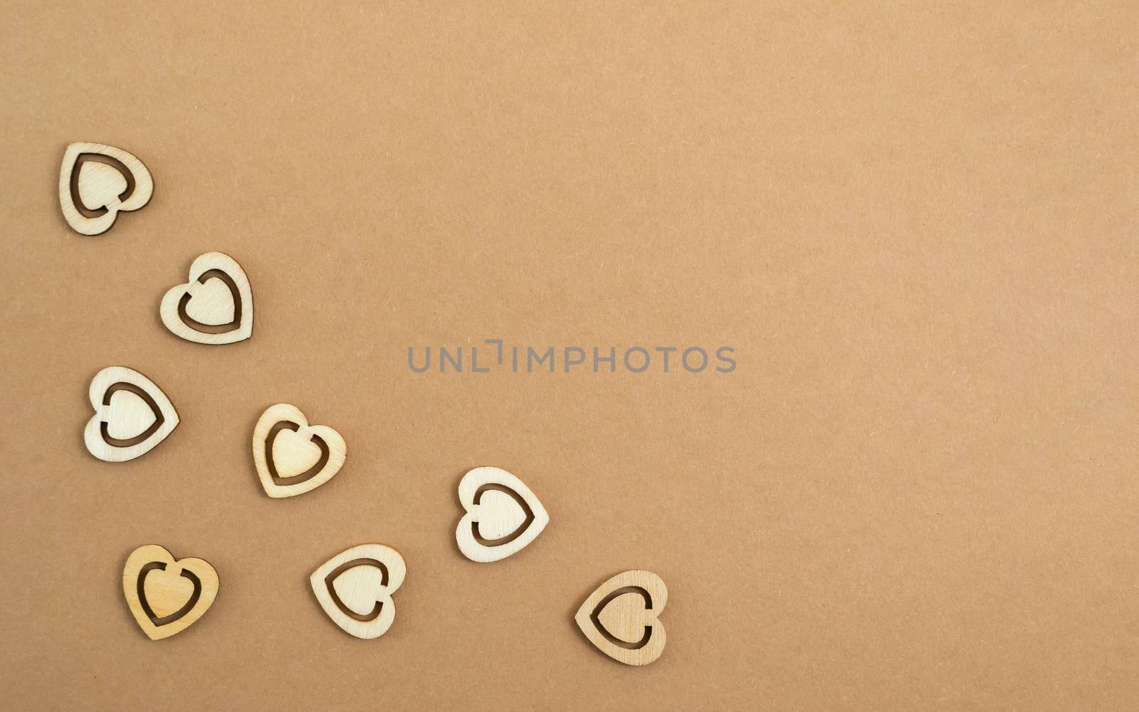 Wooden hearts on a pastel craft paper background. Abstract background with wood cut shapes. Sainte Valentine, mother's day, birthday greeting cards, invitations. Copy space.