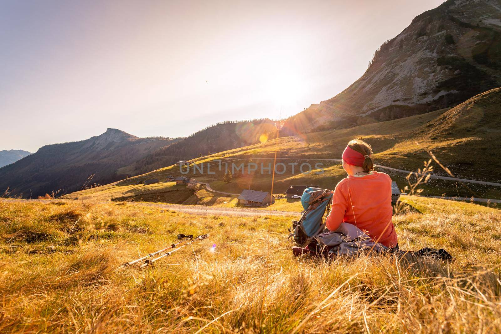 Woman in sportswear is enjoying the sunset in the mountains: sitting on the ground and enjoying the view. Alpes, Austria