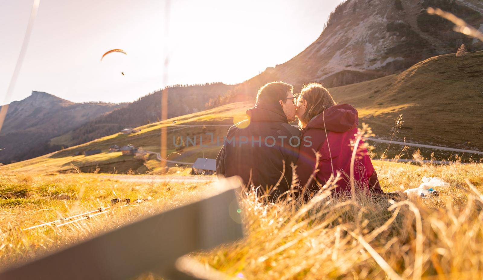 Couple in sportswear is enjoying the sunset in the mountains: sitting on the ground and enjoying the view. Alpes, Austria