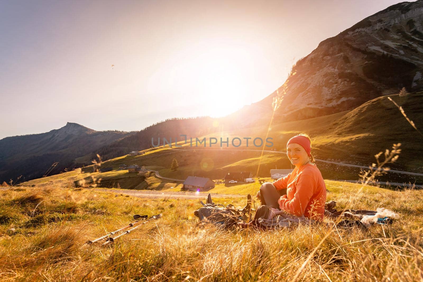 Hiking girl is enjoying the sundown in the mountains, sitting on the ground. Warm colors, alps, Austria by Daxenbichler