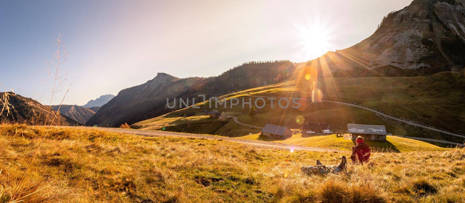 Woman in sportswear is enjoying the sunset in the mountains: sitting on the ground and enjoying the view. Alpes, Austria
