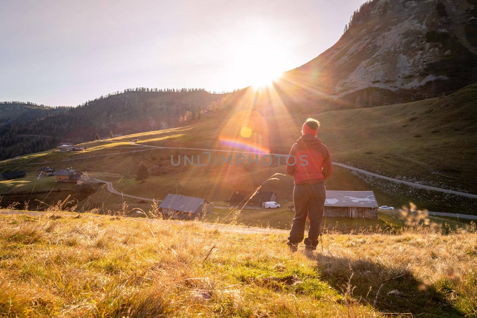 Woman in sportswear is enjoying the sunset in the mountains: sitting on the ground and enjoying the view. Alpes, Austria