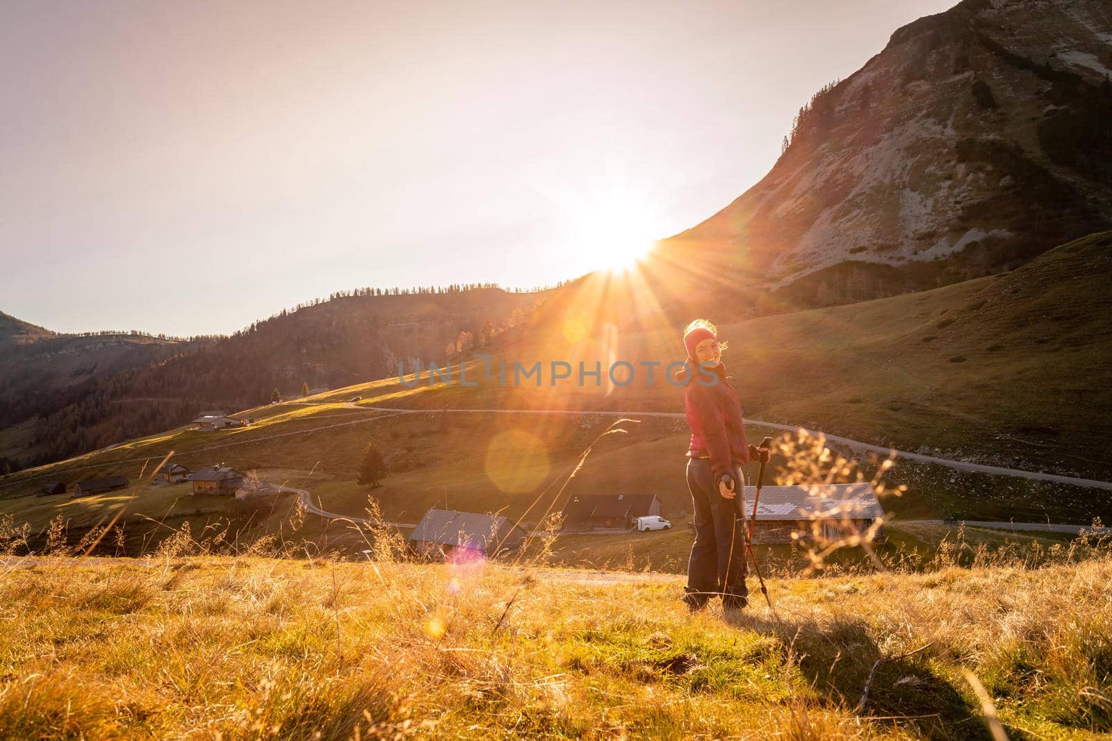 Hiking girl is enjoying the sundown in the mountains, sitting on the ground. Warm colors, alps, Austria by Daxenbichler