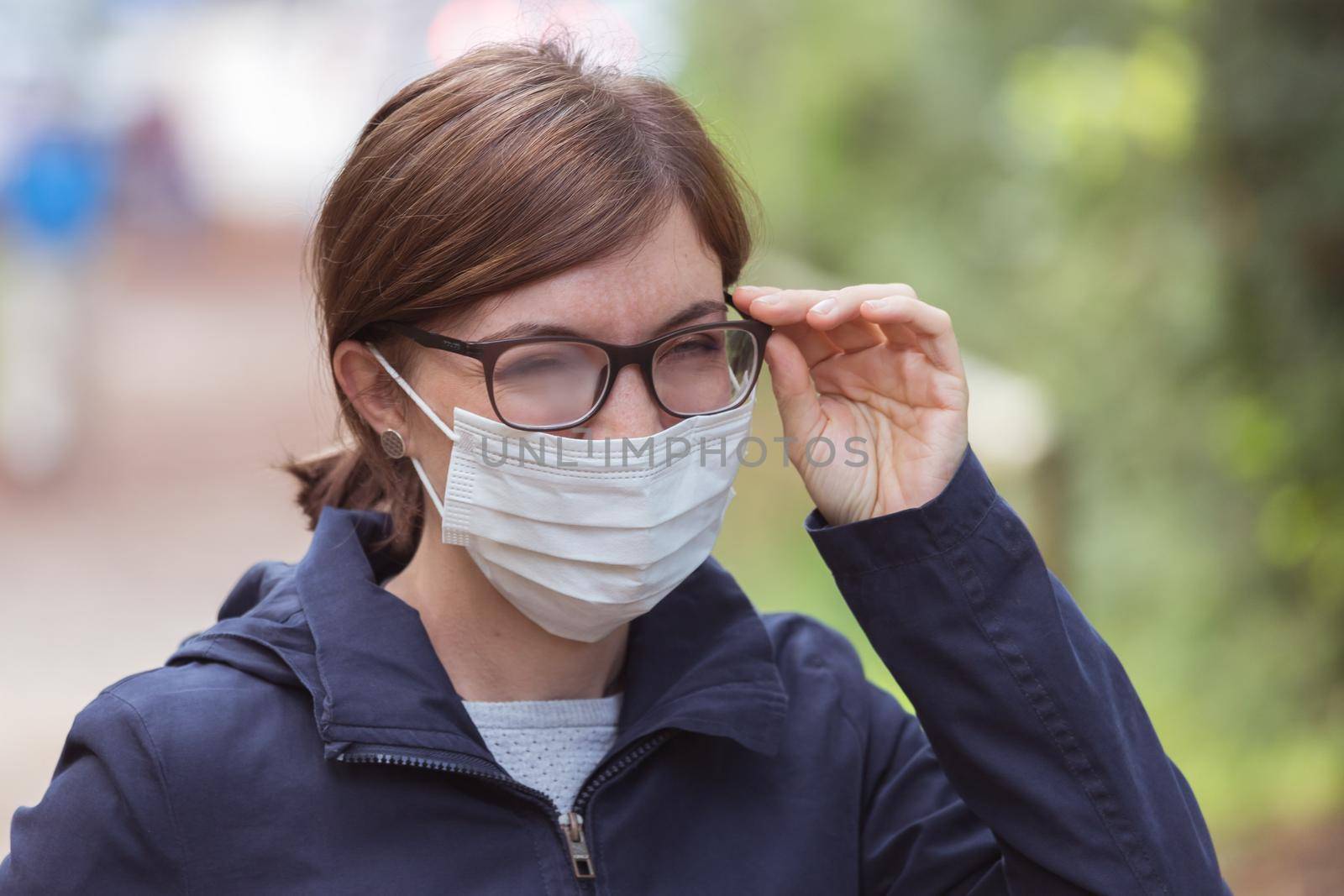 Young woman outdoors wearing a face mask and glasses, tarnished glasses