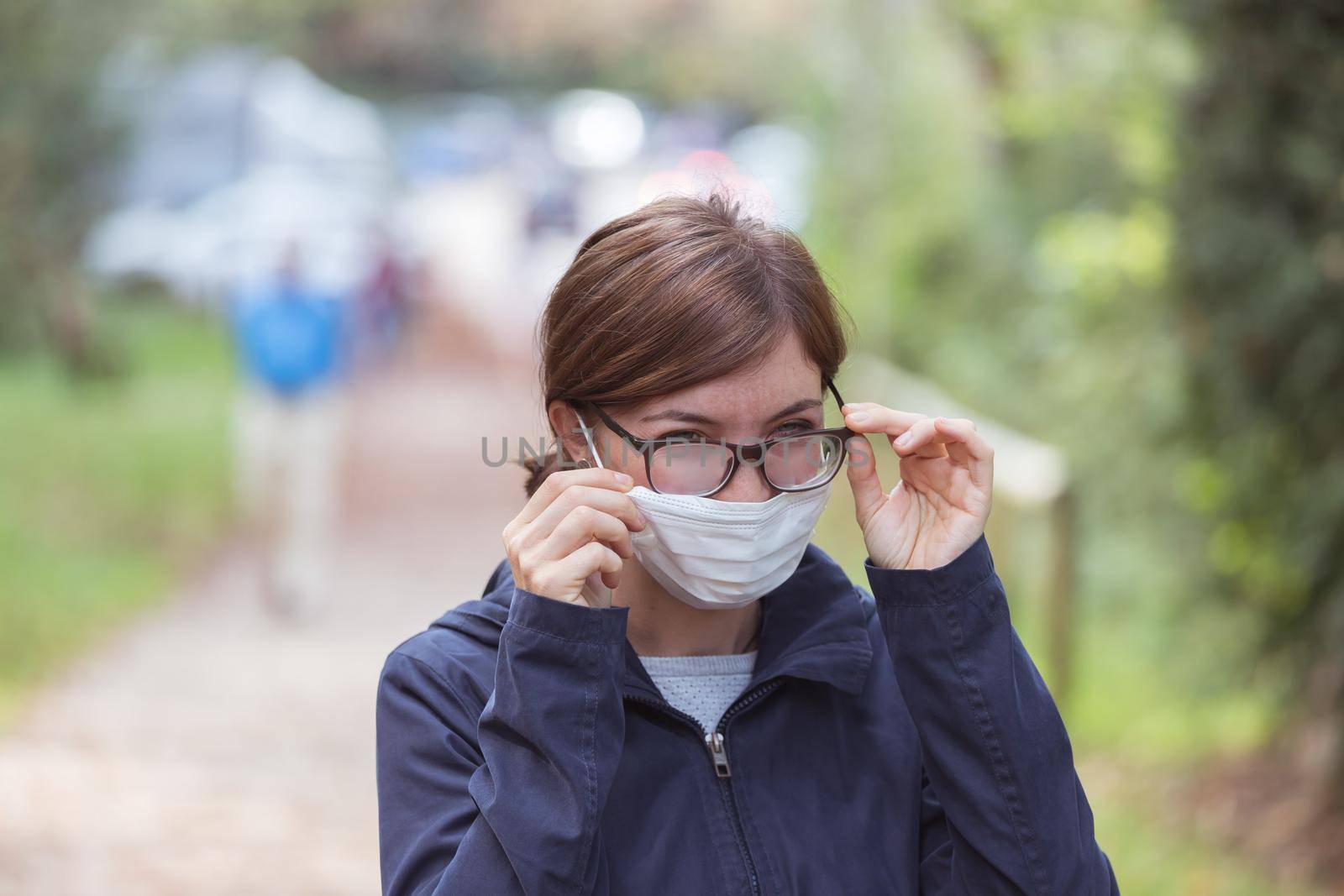 Young woman outdoors wearing a face mask and glasses, tarnished glasses