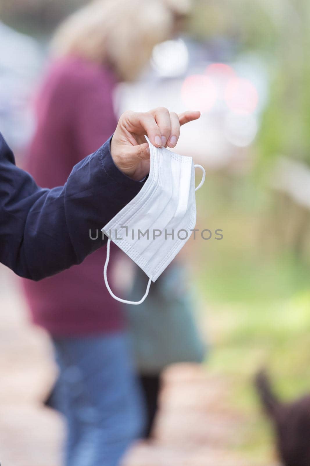 Flue and corona safety concept. Woman holding single use face mask, outdoors by Daxenbichler