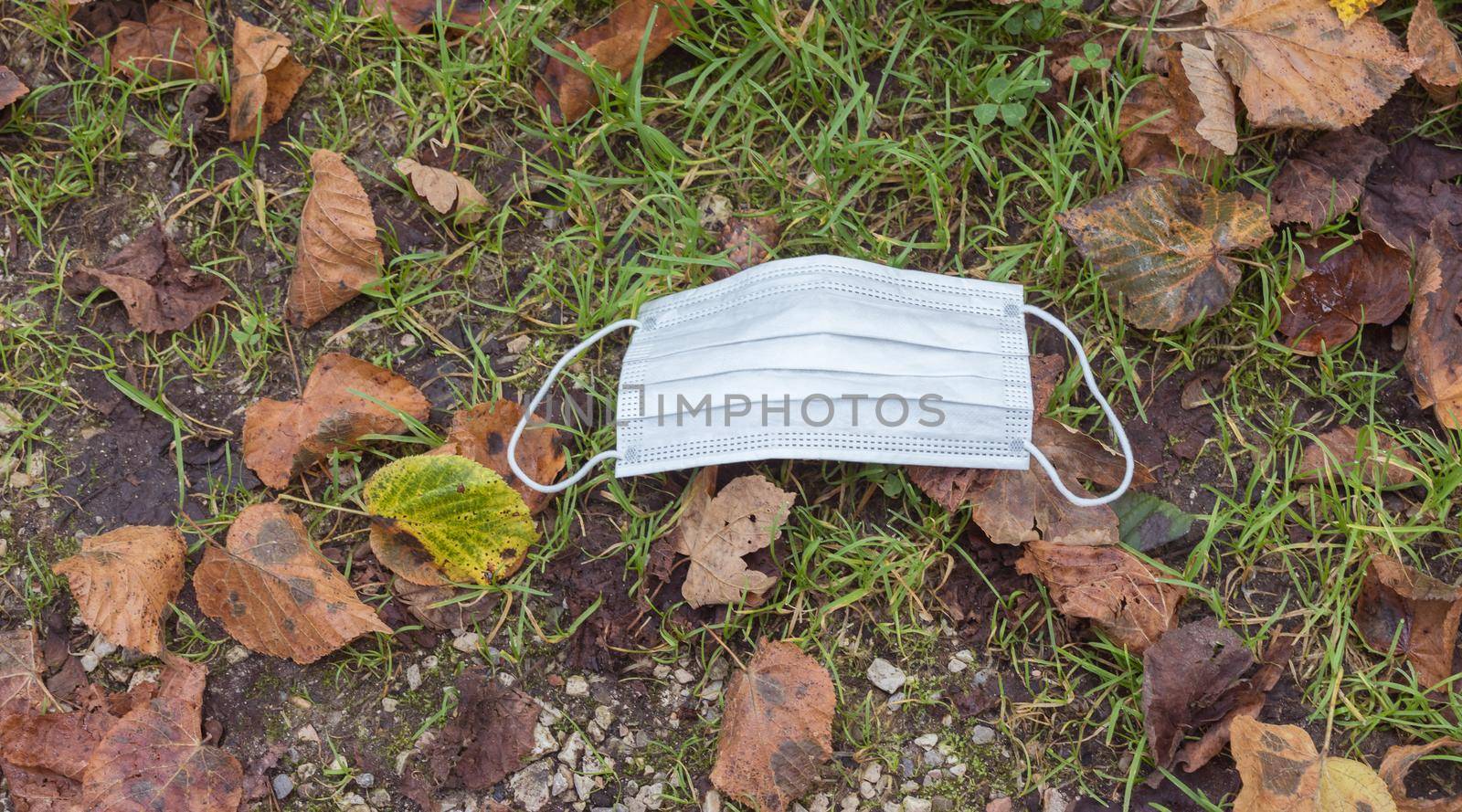 Environmental pollution concept: Single use face mask on the floor outdoors, waste
