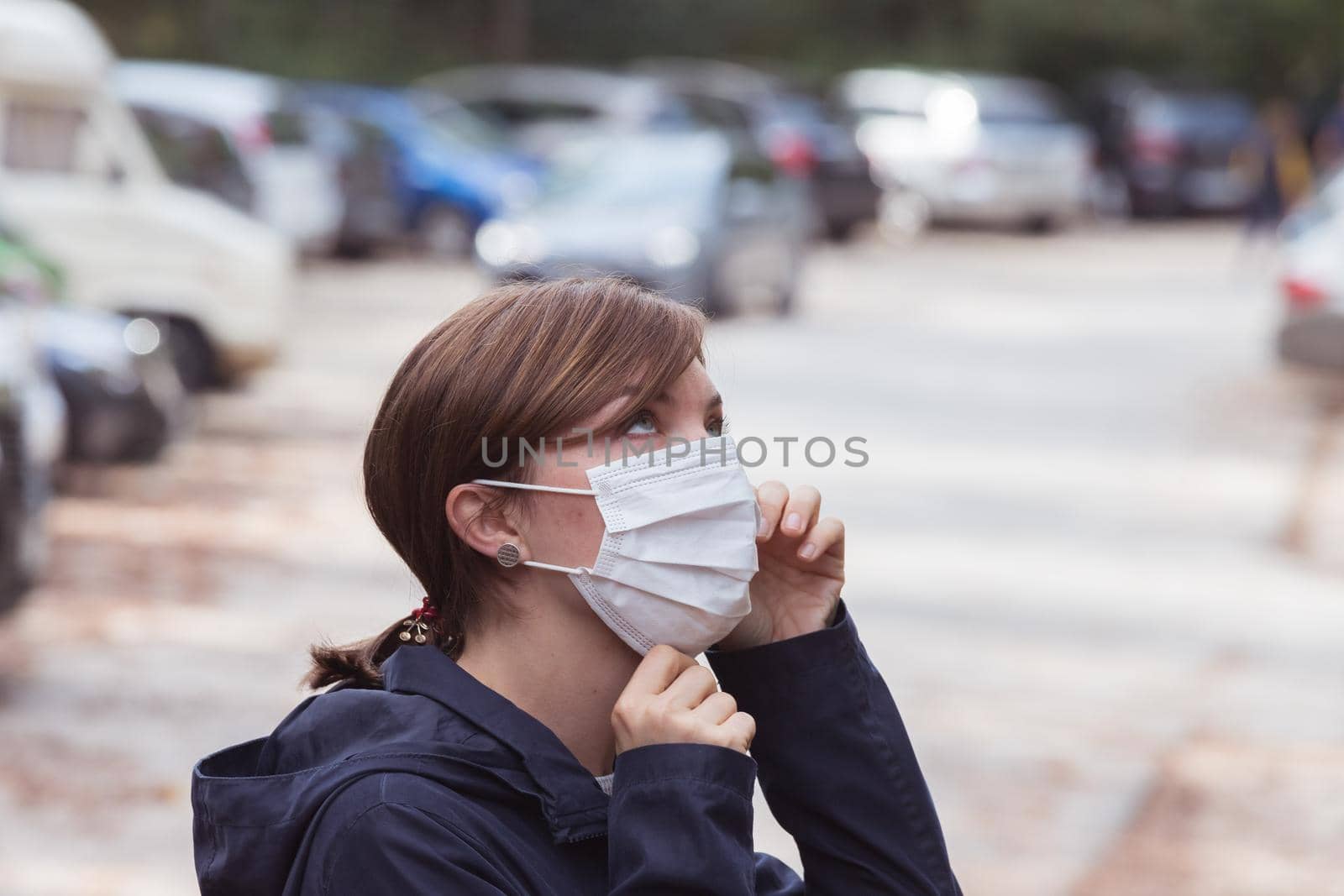 Flue and corona safety concept. Woman putting on face mask to protect herself, outdoors by Daxenbichler