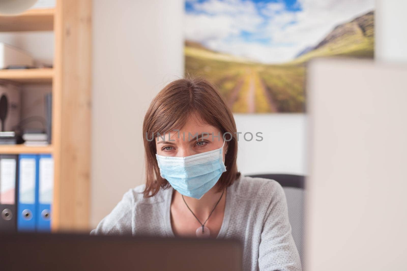 Young woman wearing face mask is working in the office during corona crisis