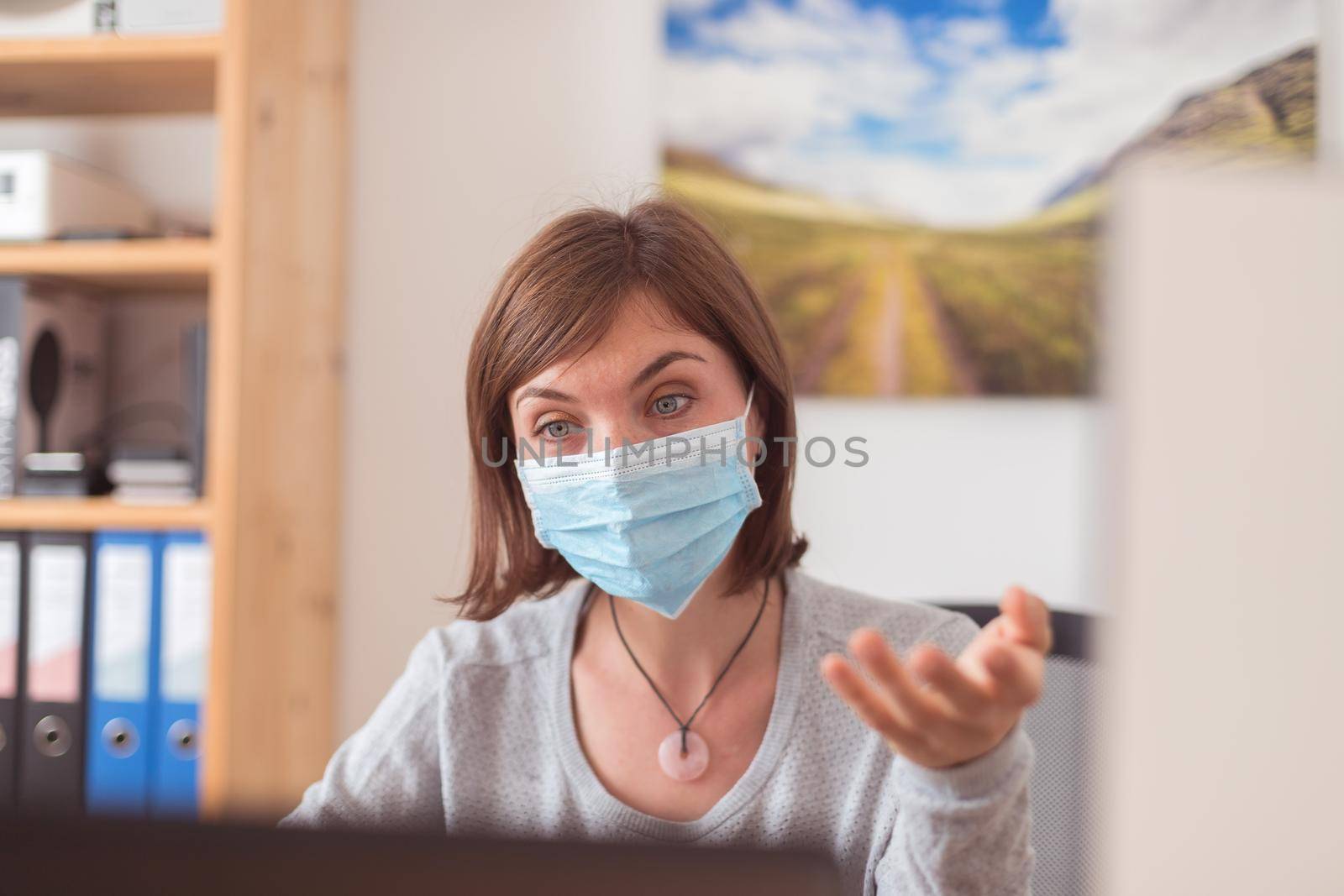 Protection in office in corona crisis: Woman with face mask is sitting on his workplace by Daxenbichler