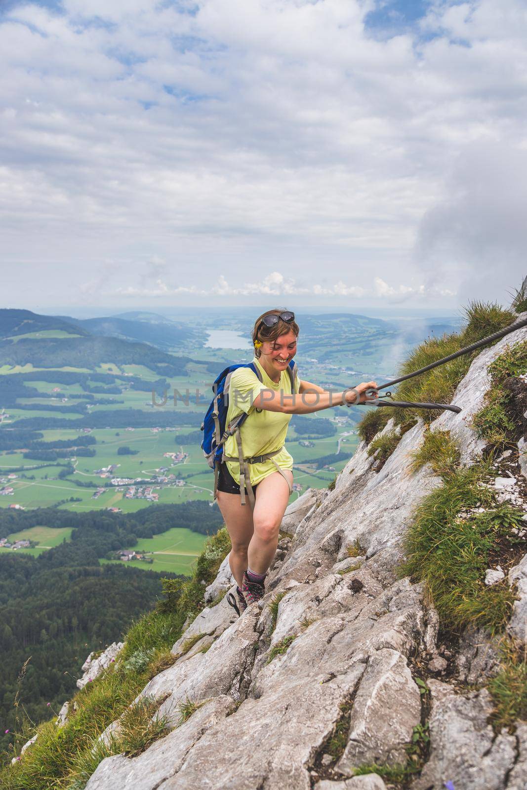 Young slim backpacker tourist girl climbing on rocky mountain, Austria