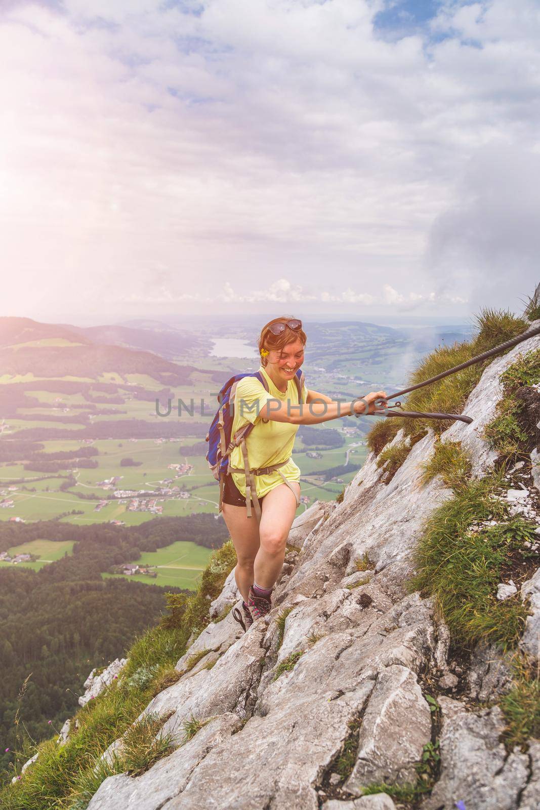 Adventure in the mountains. Young tourist girl is climbing on rocky mountain in Austria by Daxenbichler