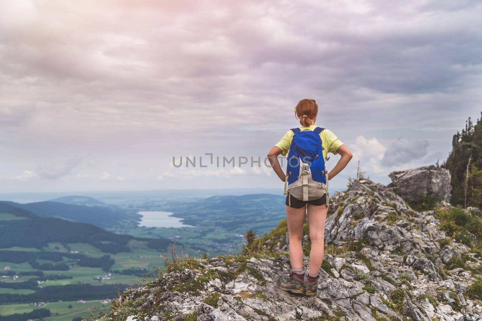 Young slim backpacker tourist girl is enjoying the view on rocky mountain, Austria