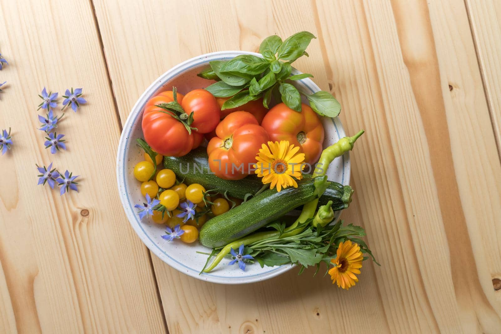 Fresh colorful vegetables in a bowl, raised in the own garden. Tomatoes, zucchini, flowers and herbs.