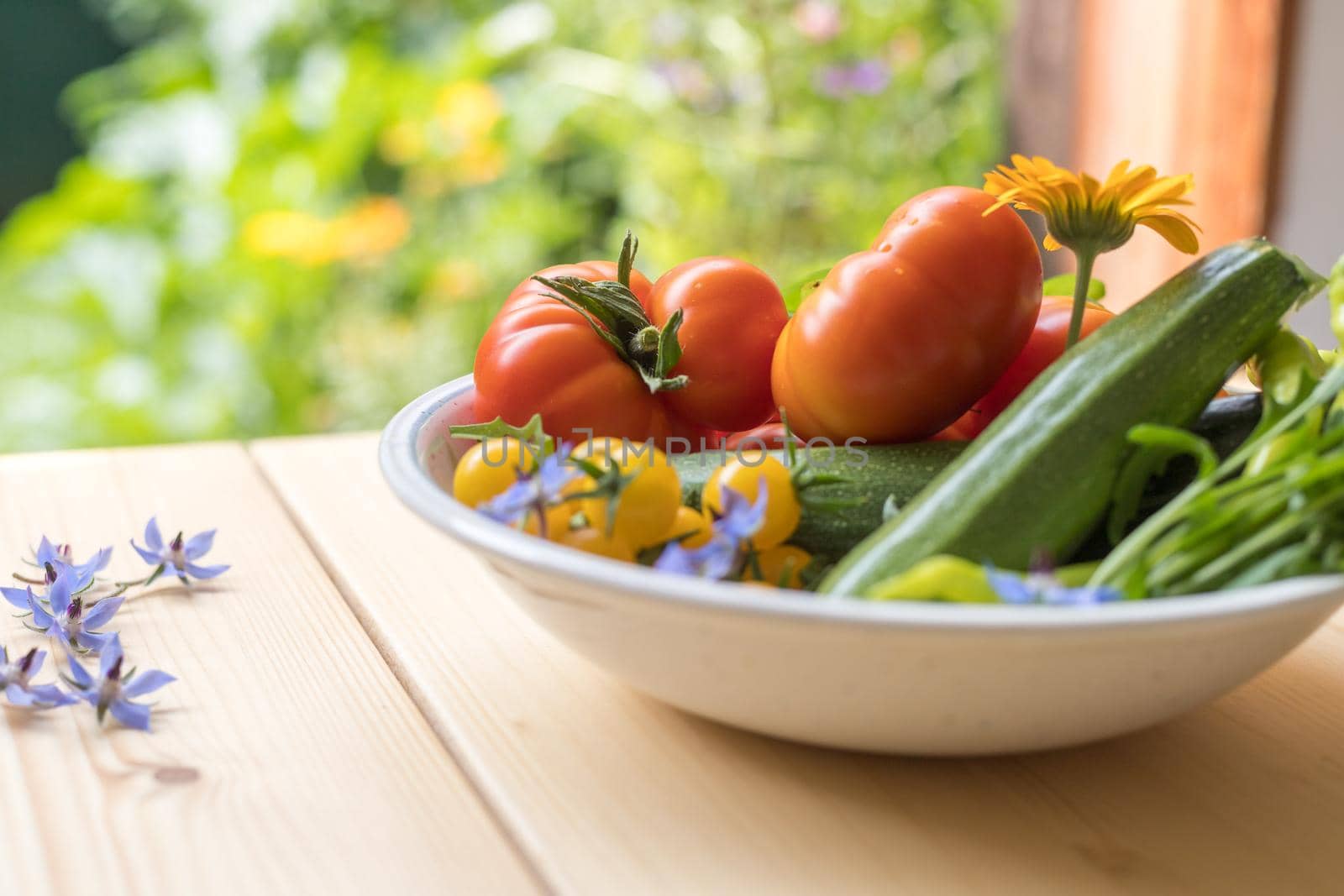 Fresh colorful vegetables in a bowl, raised in the own garden. Tomatoes, zucchini, flowers and herbs.