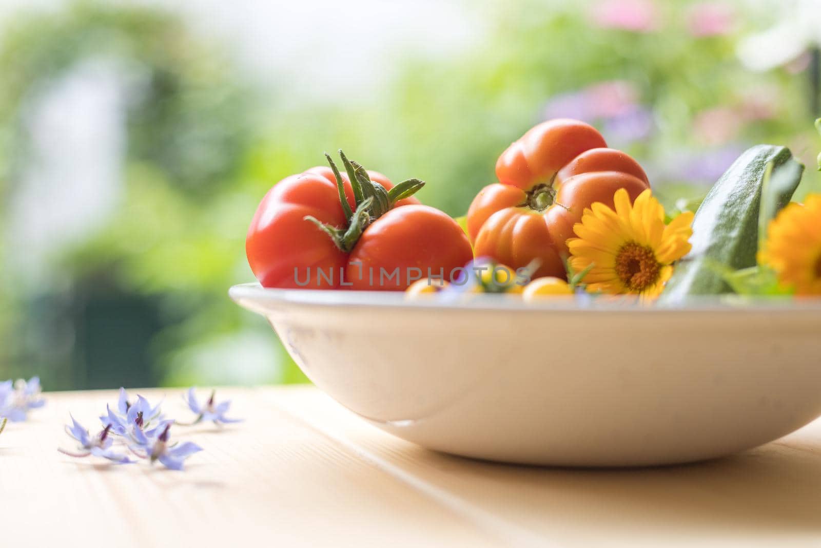 Fresh colorful vegetables in a bowl, raised in the own garden. Tomatoes, zucchini, flowers and herbs.