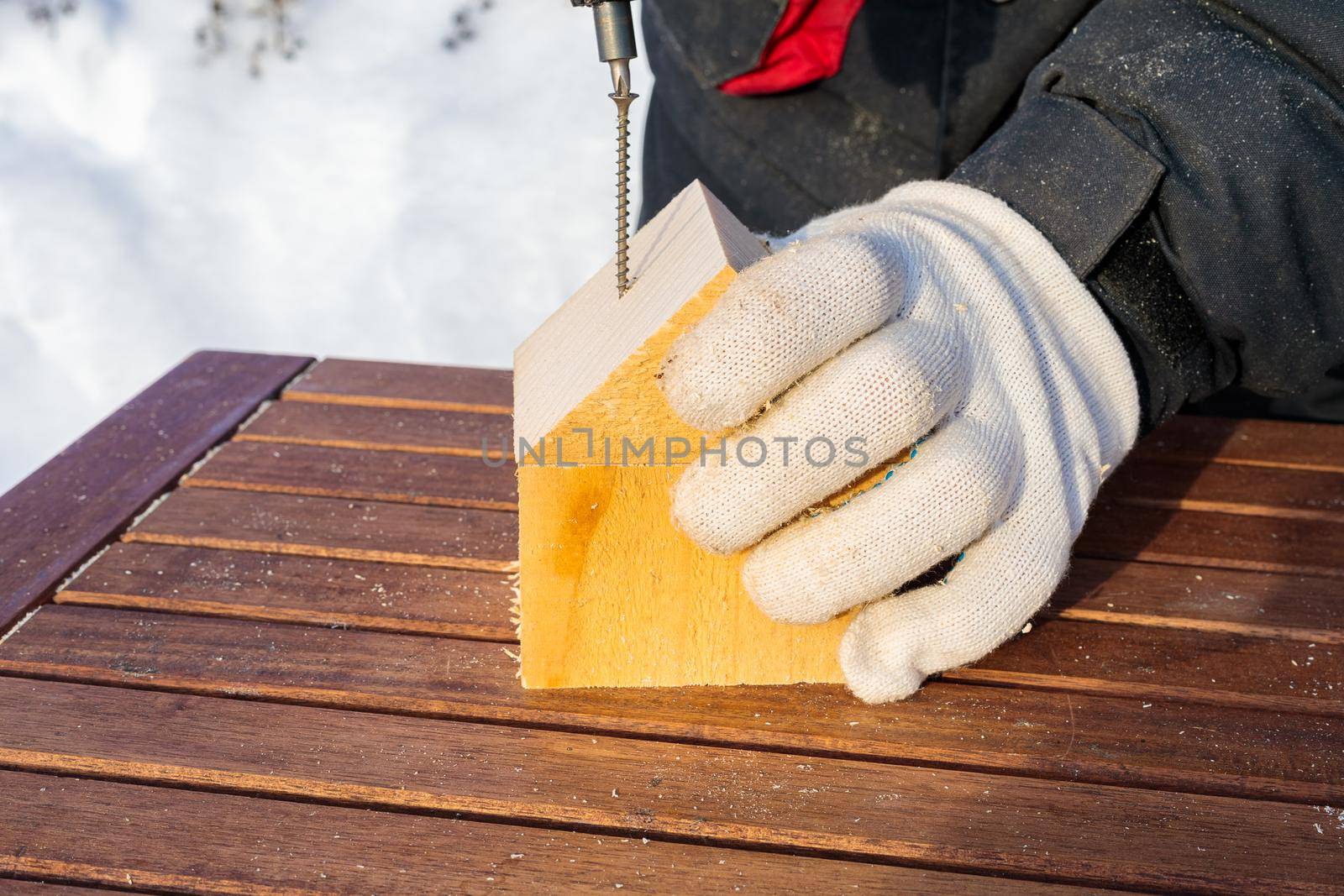 The man uses a cordless screwdriver to drive a screw into the block. Connects a cube and a triangle.