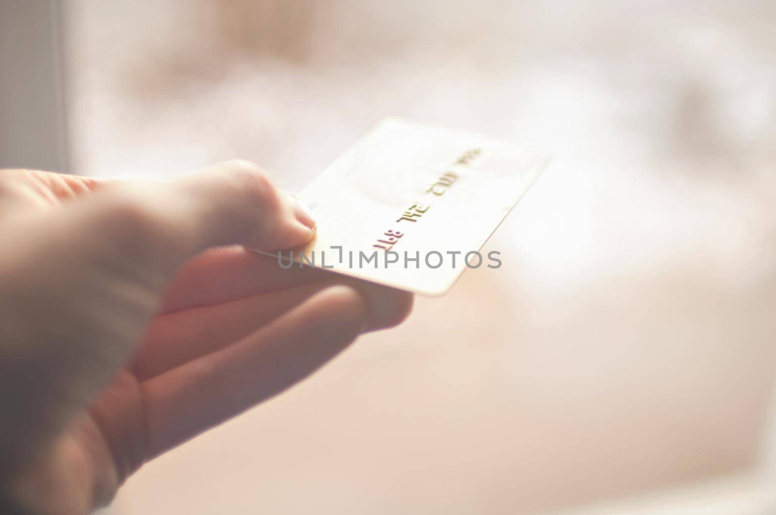 bank card of gold color in hands on a background of sunlight