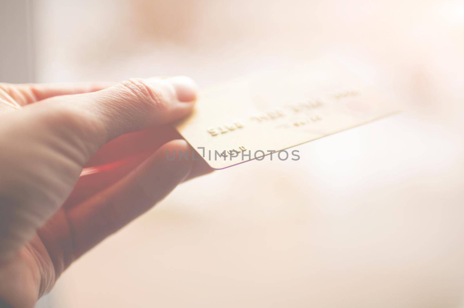 bank card of gold color in hands on a background of sunlight