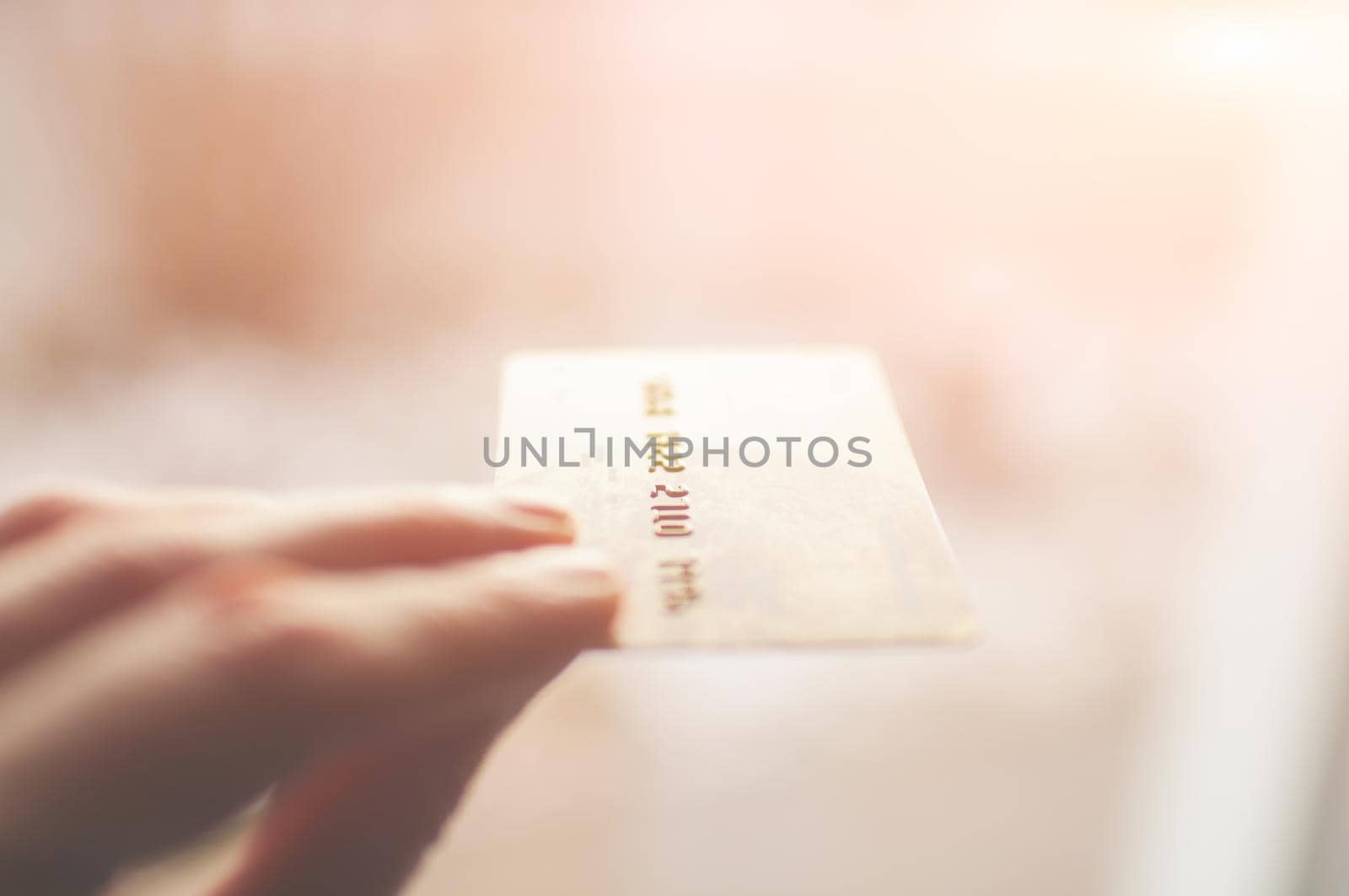 bank card of gold color in hands on a background of sunlight